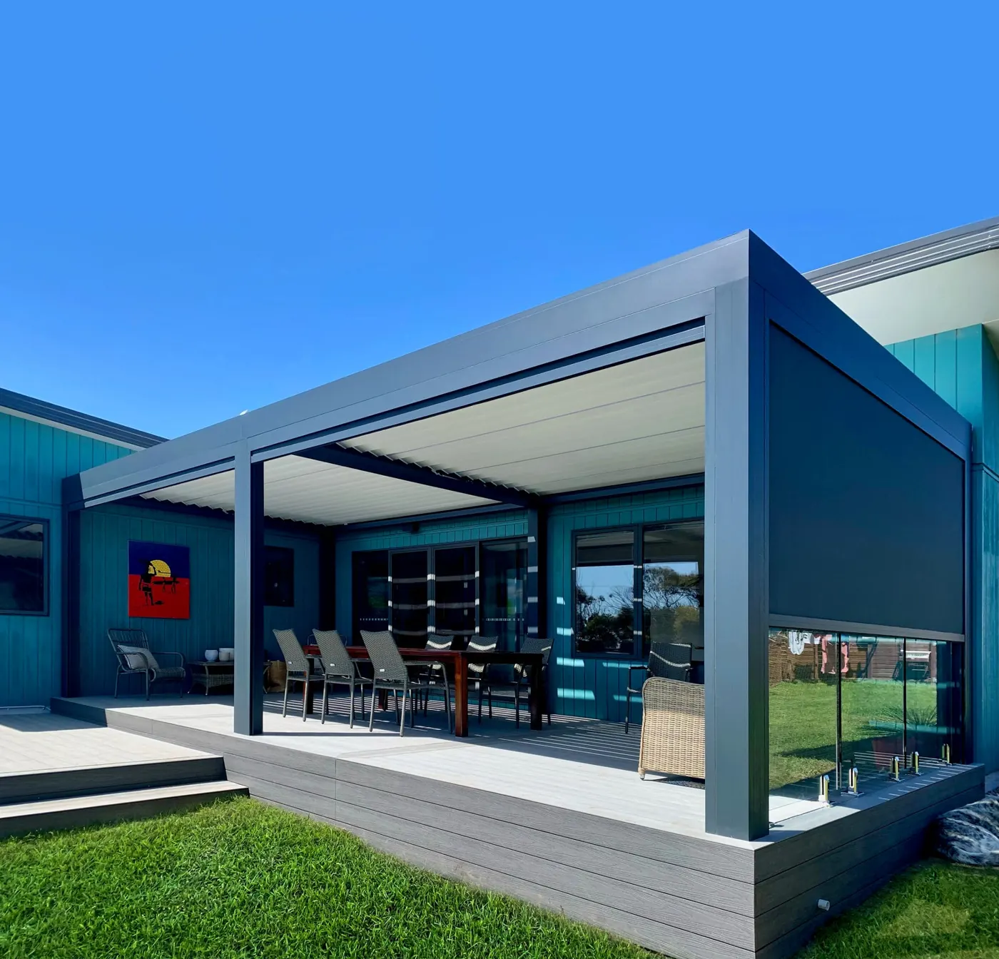 Pergola bioclimatique adossée avec store latéral, maison bleue