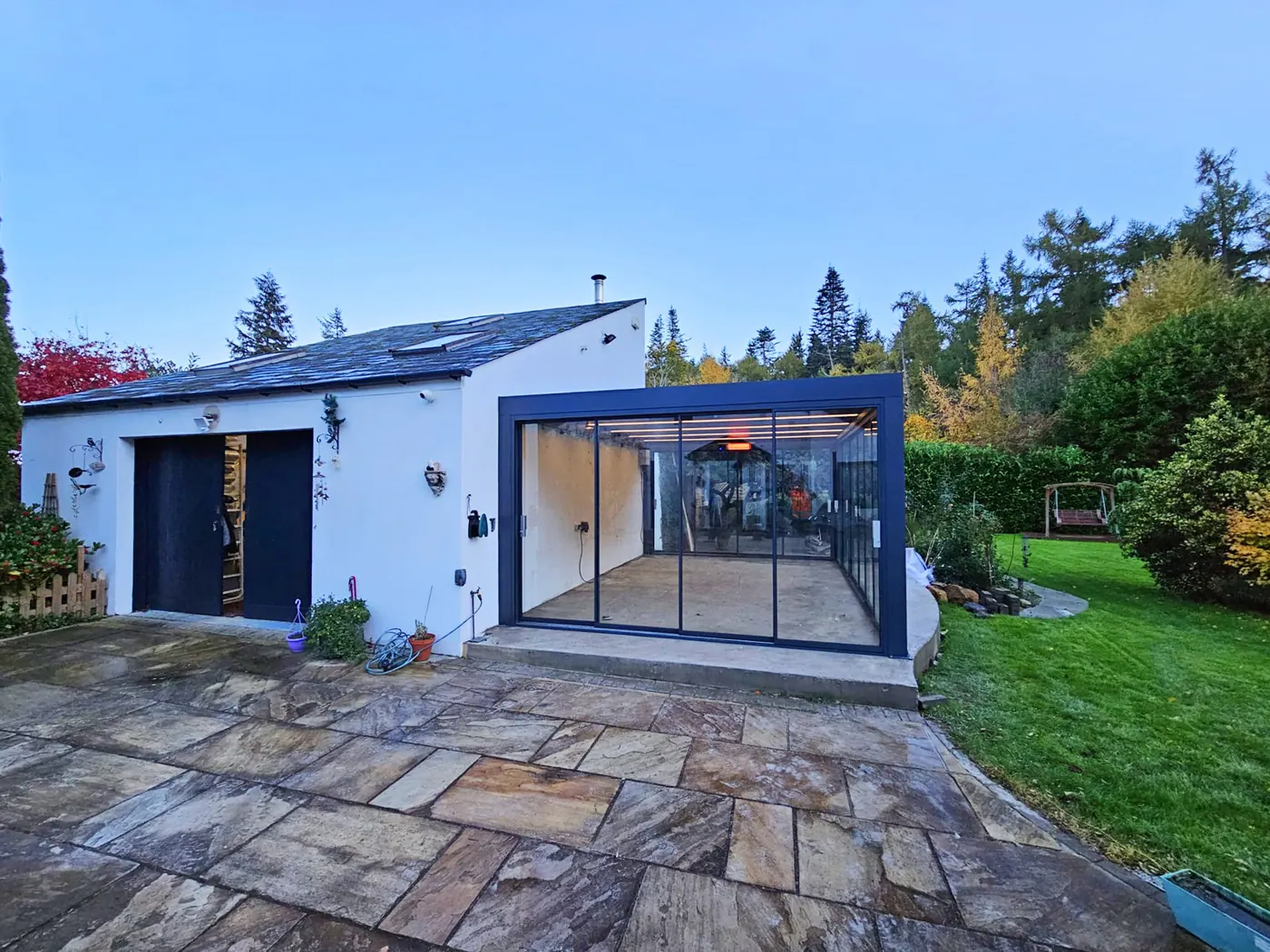 Pergola bioclimatique vitrée adossée à une maison blanche