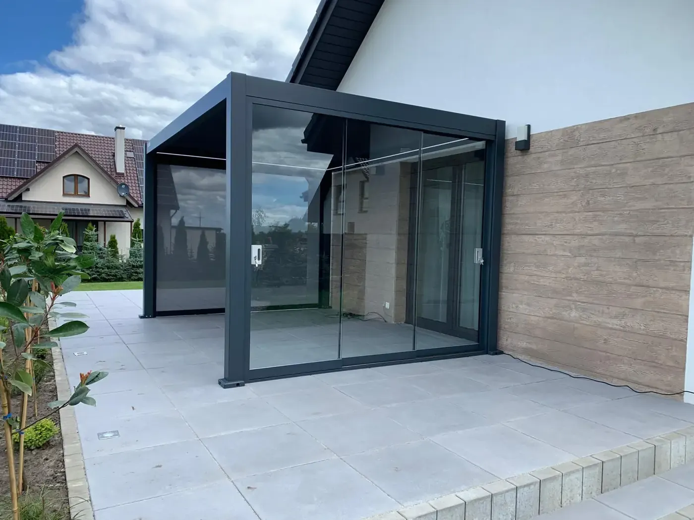 Pergola bioclimatique adossée fermée de vitres coulissantes