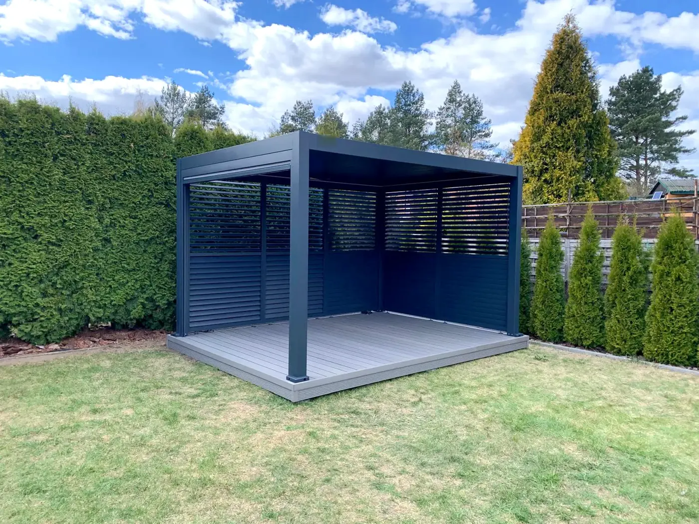 Pergola bioclimatique avec persiennes sur deux côtés, au fond du jardin